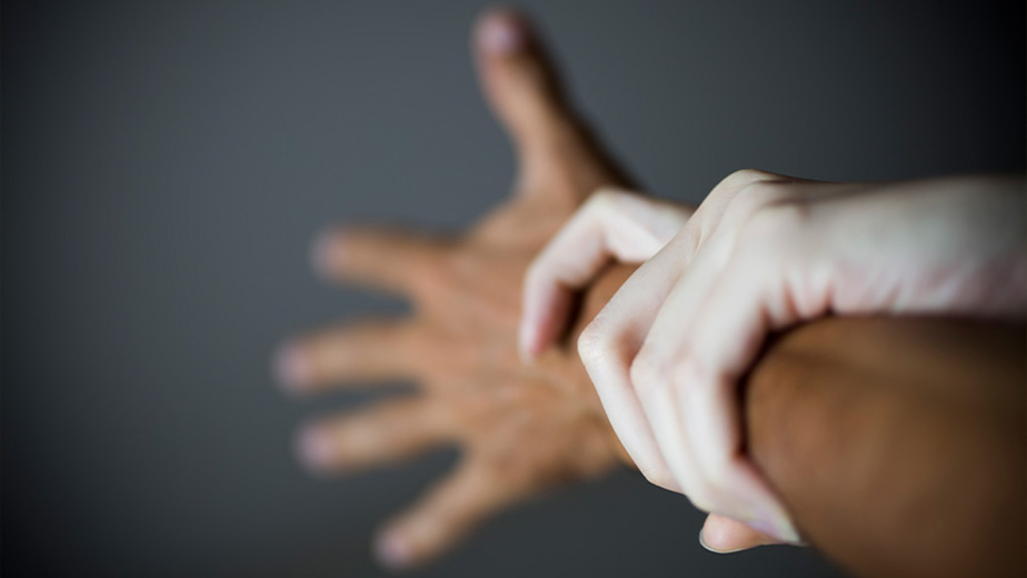 An image of a light skinned woman's hand holding the wrist of a darker-skinned male.