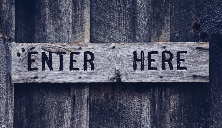 a wooden door with a wood sign with the words enter here