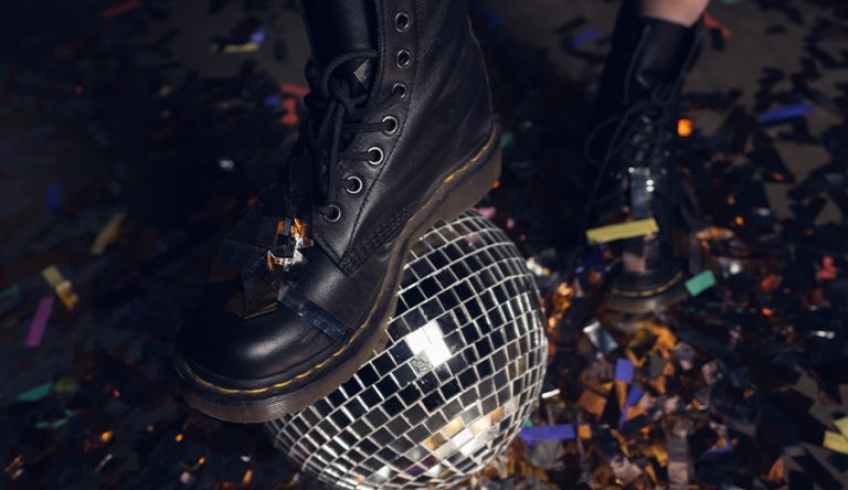 A photo of a floor filled with confetti, and a black leather boot sitting on top of a disco ball