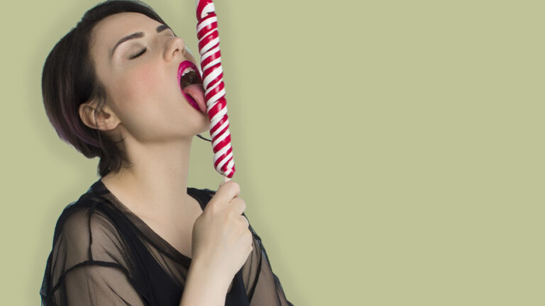 a woman in lingerie licking a long thin lollipop