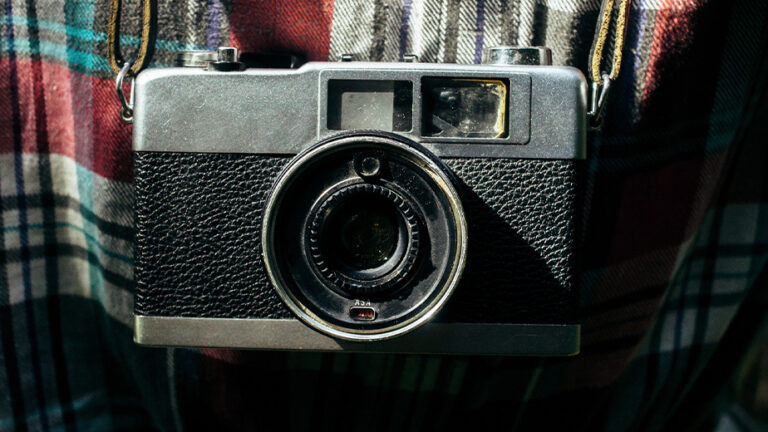 a vintage camera on top of a plaid shirt